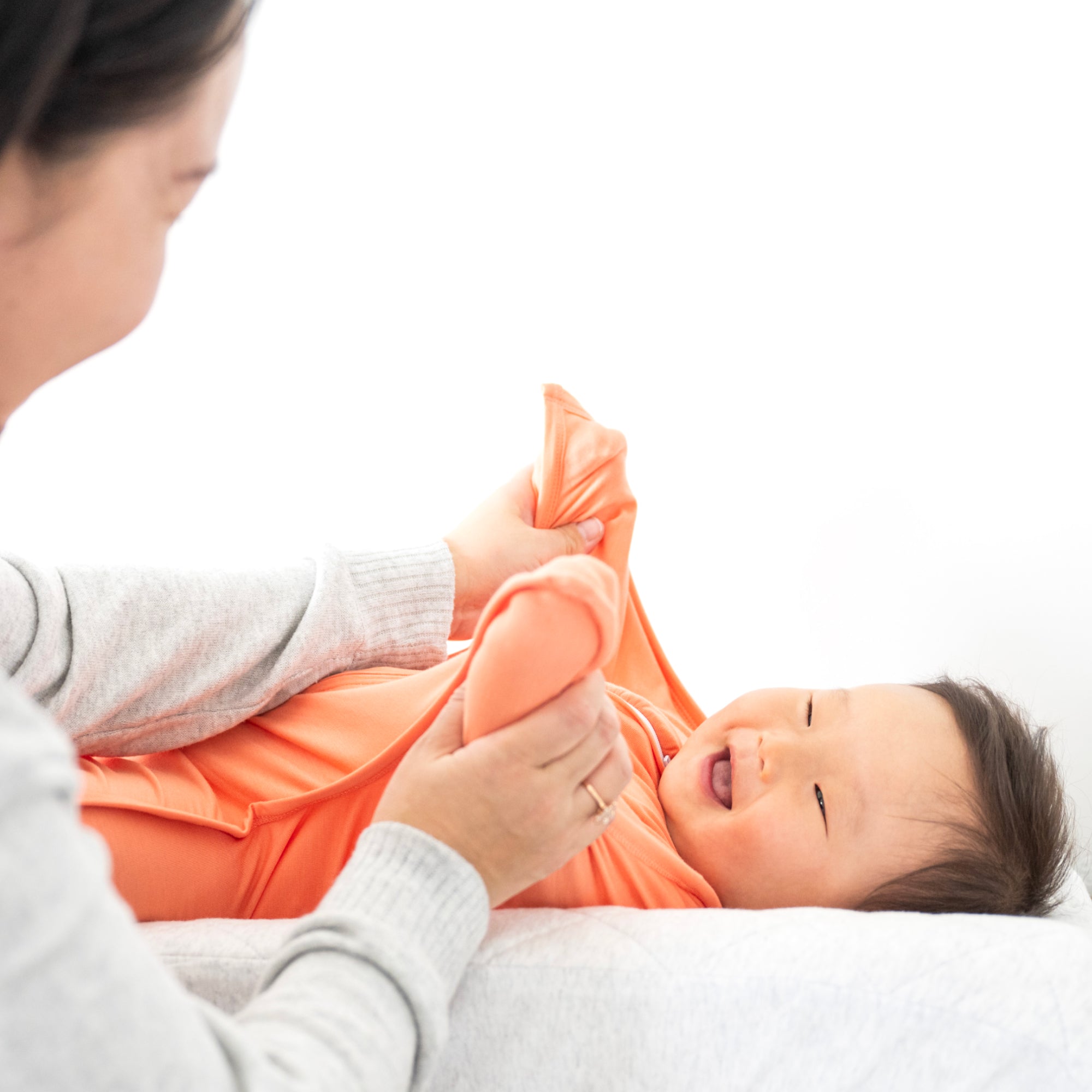 Baby smiling in Peach Fuzz bamboo swaddle transition