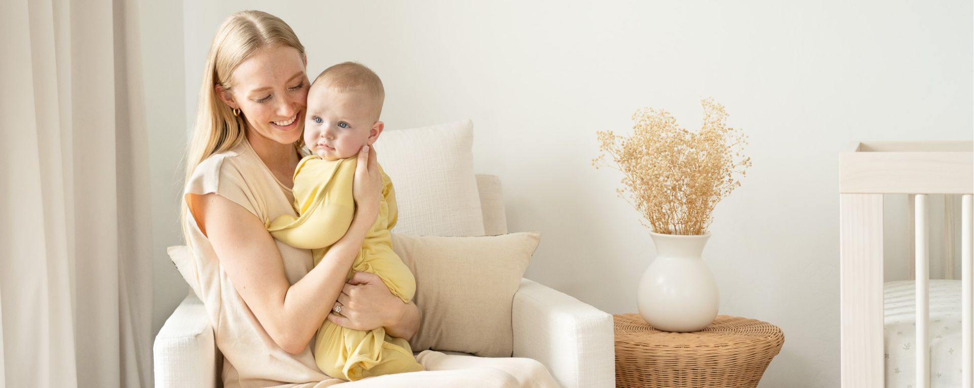 Woman holding a baby in a yellow zipadee-zip in a nursey.