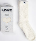 Load image into Gallery viewer, White fluffy lounge sock next to its packaging with 'LOVE by Little Giraffe' branding on a light gray background.
