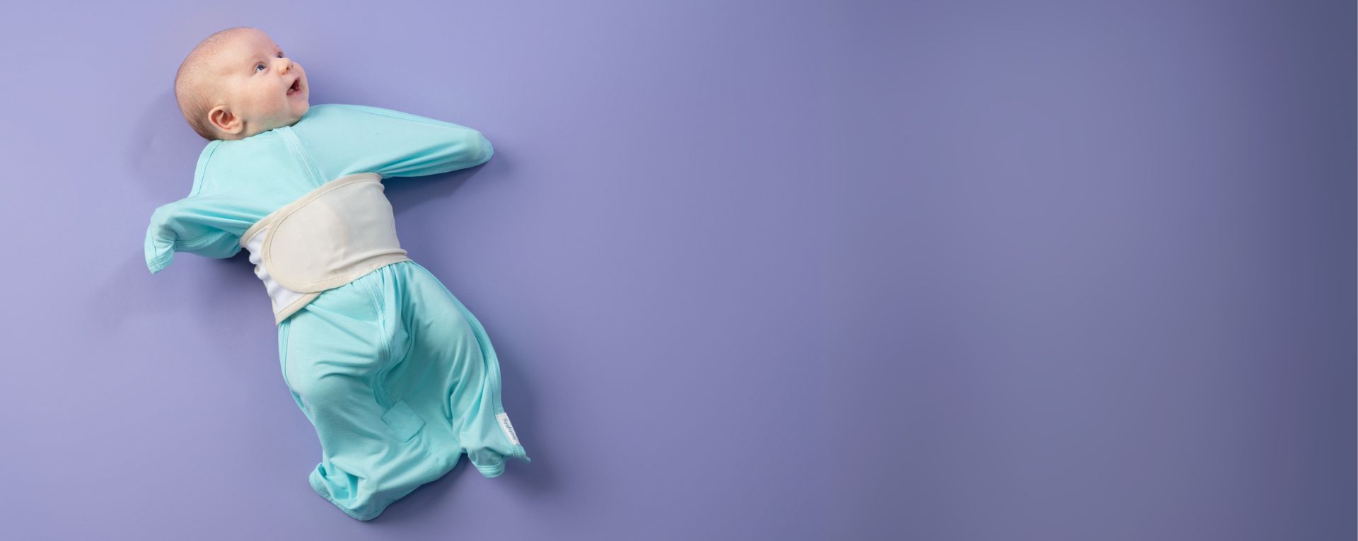 Baby wrapped in a light blue swaddle on a purple background